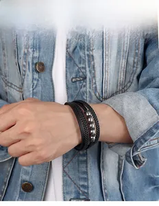 Gros plan d'un bracelet multicouche en cuir PU tressé avec perles argentées sur denim