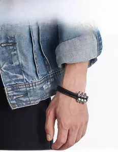 Close-up of punk leather bracelet with six silver skull pendants worn by a male model