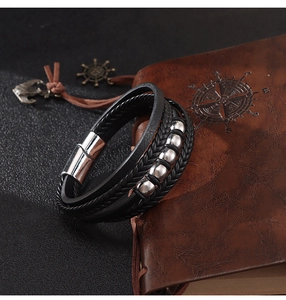 Détail du bracelet multicouche en cuir tressé noir avec perles argentées et fermoir aimanté