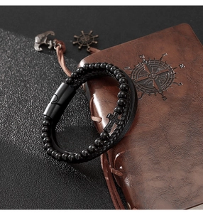Dettaglio del bracciale multistrato in pelle con croce e perle di onice su pelle vintage