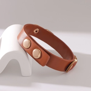 Braunes zweilagiges Lederarmband mit goldenen Metalldruckknöpfen auf einem Display
