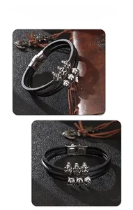 Macro detail of multi-layer black leather bracelet with silver skull charms and metal clasp