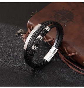 Macro detail of multilayer woven leather bracelet with magnetic clasp on vintage notebook