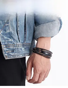 Nahaufnahme eines mehrlagigen geflochtenen Lederarmbands für Herren mit Jeansjacke