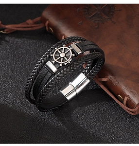 Detailansicht eines mehrlagigen Lederarmbands mit silbernem Steuerrad-Anhänger und Magnetverschluss