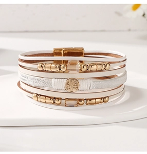 Macro detail of multi-layer white leather bracelet with golden Tree of Life magnetic clasp