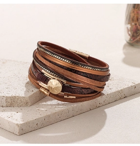 Detail of multi-layer brown snake pattern leather bracelet with a magnetic gold metal clasp
