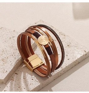 Detail of multi-layer leather bracelet featuring gold magnetic clasp and metal beads