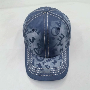 Detailed close-up of blue washed denim baseball cap with white contrast stitching and prints