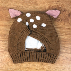 Detail of baby knitted hat with deer ear design and white dots on brown yarn