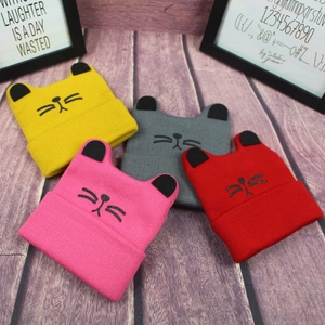 Detailed close-up of cute cat ear knit hats in yellow, pink, gray, and red colors