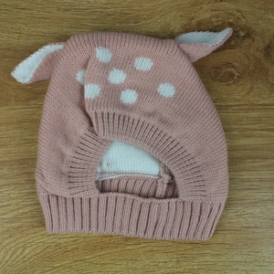 Detailed view of pink knitted baby hat with white polka dots and deer animal ears