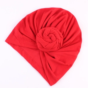 Détail de la texture d'un turban rouge avec un nœud décoratif en forme de rose
