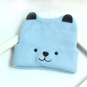 Détail d'un bonnet en tricot bleu clair pour bébé avec oreilles et broderie d'ours