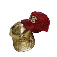 Detail view of gold and red faux snakeskin baseball caps with diamond dollar sign