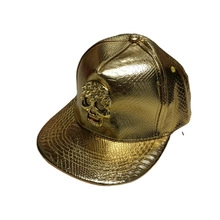 Detailed view of the gold faux snakeskin snapback hat with 3D skull emblem on the front