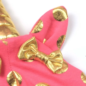 Close-up of pink knit fabric featuring metallic gold polka dots and a decorative bow detail