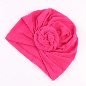 Détail d'un bonnet turban rose fuchsia avec un nœud de rose fait main et coutures fines