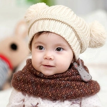 Close-up of knit baby winter hat with double pom-poms and warm brown infinity scarf