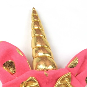 Detailed macro view of a pink knitted hat featuring a golden spiral unicorn horn and ears