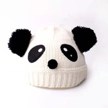 Detail of panda knit hat with dual black pom-poms and cute embroidered animal facial features