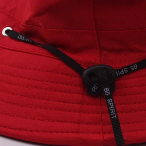 Détail du chapeau bob rouge montrant la jugulaire réglable et la texture du tissu ripstop