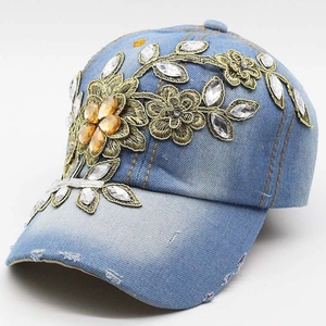 Detail of floral gold embroidery and sparkling rhinestones on light blue denim baseball cap