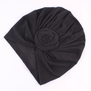 Gros plan d'un turban noir avec nœud floral en 3D et détails plissés élégants