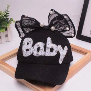 Dettaglio di un cappello nero per bambini con fiocco in pizzo, perle e scritta Baby
