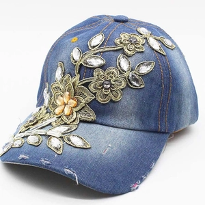 Close-up of blue denim baseball cap with golden floral embroidery and crystal rhinestones