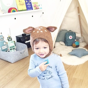 Detail of cute baby deer knit hat with ears shown in a cozy indoor playroom setting