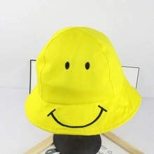 Detailed view of yellow cotton bucket hat featuring a black printed smiley face design