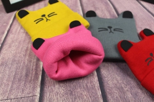 Detailed view of knitted cat ear hats with embroidery in yellow, pink, gray, and red colors
