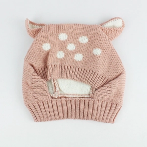 Detailed knit texture of pink deer ear baby hat with white polka dots and ribbed edge