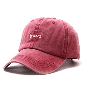 Close-up of Yours embroidery on a vintage burgundy washed cotton baseball cap texture