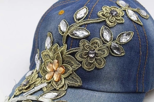 Close-up of luxury gold embroidery and rhinestones on deep blue denim baseball cap