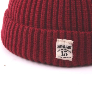 Close-up of wine red knit hat texture and white rectangular woven label with text