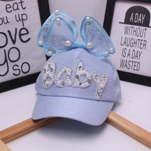 Dettaglio cappellino neonato con fiocco in pizzo, perle e ricamo di paillettes