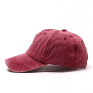Detail view of burgundy washed cotton baseball cap showing side letter embroidery and texture