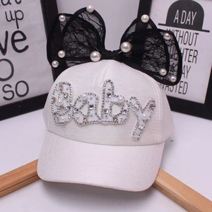 Dettaglio cappellino bimba con fiocco in pizzo, perle e ricamo di lettere in strass