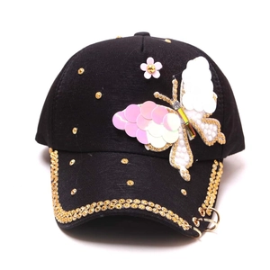 Détail d'une casquette de baseball noire avec applique papillon et anneau en métal doré