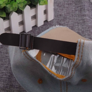 Close-up of adjustable leather strap and metal buckle on blue denim baseball cap
