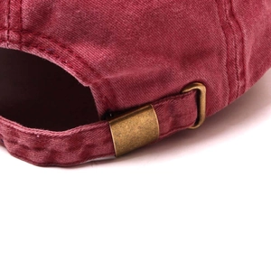 Detailed close-up of adjustable bronze metal buckle on vintage washed red baseball cap