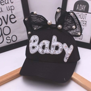 Dettaglio cappellino nero per bambine con scritte in perle Baby e fiocco di pizzo