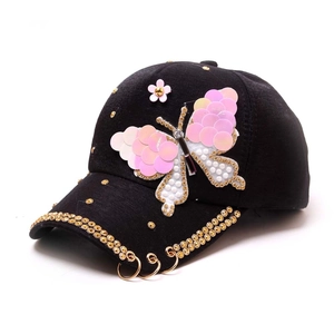 Casquette noire avec papillon en paillettes roses, strass et anneaux dorés