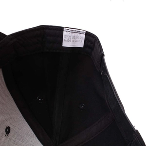 Detail of the internal wash label showing 100% cotton material on black baseball cap