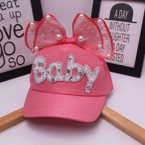 Dettaglio cappellino rosa per bambini con fiocco in pizzo, perle e scritte baby in strass