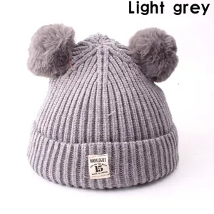 Winter knitted baby hat in light grey with cute double pom poms and soft wool texture
