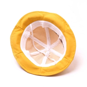 Detail view of yellow cotton bucket hat interior with windproof rope and white lining