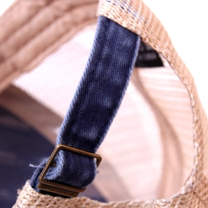 Macro view of adjustable copper buckle and denim strap on beige mesh trucker hat